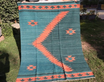 May include: A teal and orange handwoven rug with a geometric pattern. The rug has a fringe border and is made of wool.