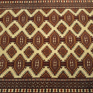 May include: A beige rug with a repeating geometric pattern in shades of red, brown, and green. The pattern features diamonds and hexagons.