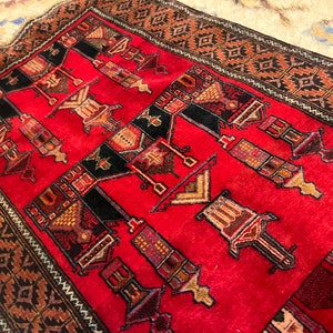 Peut inclure: Un tapis de prière rouge avec un motif géométrique en noir, marron et beige. Le tapis a une bordure à franges.