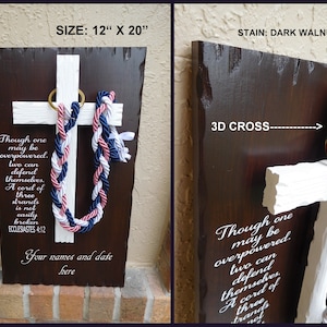 May include: A dark walnut stained wooden plaque with a white 3D cross. The cross has a braided rope in pink, white, and blue hanging from it. The plaque has the text "Though one may be overpowered, two can defend themselves. A cord of three strands is not easily broken. Ecclesiastes 4:12" and "Your names and date here". The plaque measures 12 inches by 20 inches.