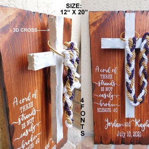 Peut inclure: Une plaque en bois rectangulaire de 30,48 cm sur 50,8 cm avec une croix 3D blanche fix&eacute;e. Un anneau dor&eacute; retient des cordes tress&eacute;es blanches, dor&eacute;es et violettes. Le texte blanc indique : A cord of three strands is not easily broken, Ecclesiastes 4:12, Jordan and Kayla, July 10, 2021.