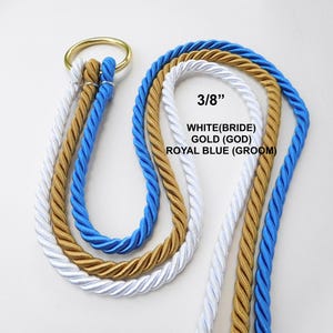 Peut inclure: Trois cordes torsad&eacute;es de couleur blanche, dor&eacute;e et bleu roi, d'un diam&egrave;tre de 3/8 de pouce, sont pass&eacute;es dans un anneau m&eacute;tallique dor&eacute;. Le texte sur l'image indique : 3/8 inch, WHITE (BRIDE), GOLD (GOD), ROYAL BLUE (GROOM).