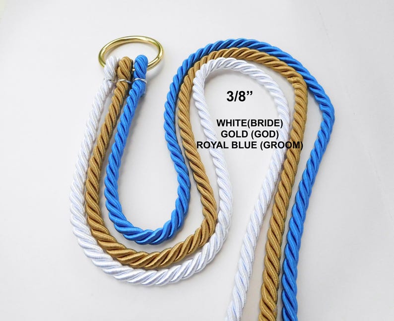 Peut inclure: Trois cordes torsad&eacute;es de couleur blanche, dor&eacute;e et bleu roi, d'un diam&egrave;tre de 3/8 de pouce, sont pass&eacute;es dans un anneau m&eacute;tallique dor&eacute;. Le texte sur l'image indique : 3/8 inch, WHITE (BRIDE), GOLD (GOD), ROYAL BLUE (GROOM).
