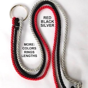 May include: Three twisted ropes in red, black, and silver colors attached to a single circular metal ring. The text RED BLACK SILVER is printed in the center, and the text MORE: COLORS RINGS LENGTHS is printed below it on the ropes.