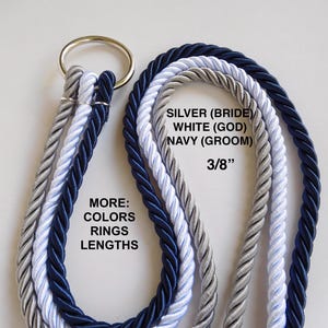 Op de afbeelding: Drie gedraaide touwen in zilver, wit en marineblauw, verbonden met een gouden ring. De tekst op de afbeelding luidt "SILVER (BRIDE) WHITE (GOD) NAVY (GROOM) 3/8" en "MORE: COLORS RINGS LENGTHS."