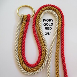 Peut inclure: Trois cordes torsad&eacute;es de couleurs ivoire, or et rouge attach&eacute;es &agrave; un anneau m&eacute;tallique de couleur laiton. Les cordes ont un diam&egrave;tre de 3/8 de pouce. Le texte IVORY GOLD RED 3/8" est imprim&eacute; en noir sur le c&ocirc;t&eacute; droit des cordes.