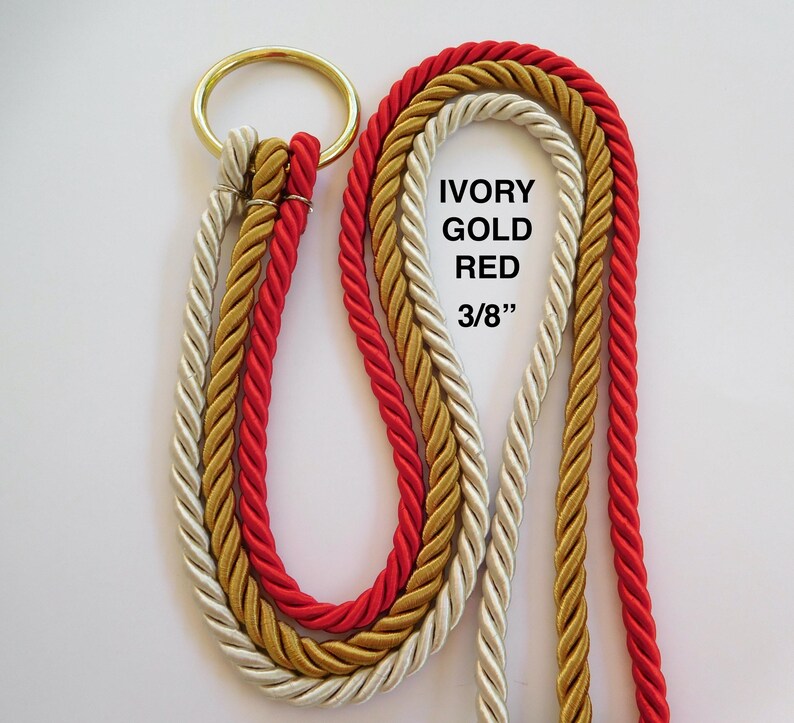 Peut inclure: Trois cordes torsad&eacute;es de couleurs ivoire, or et rouge attach&eacute;es &agrave; un anneau m&eacute;tallique de couleur laiton. Les cordes ont un diam&egrave;tre de 3/8 de pouce. Le texte IVORY GOLD RED 3/8" est imprim&eacute; en noir sur le c&ocirc;t&eacute; droit des cordes.