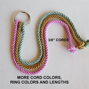 Op de afbeelding: Drie gedraaide koorden in roze, goud en teal, elk 1 cm dik, zijn gelust en geknoopt. Een set is bevestigd aan een zilveren ring. Tekst luidt "3/8" CORDS" en "MORE CORD COLORS, RING COLORS AND LENGTHS".