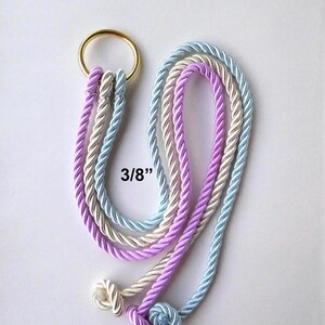 May include: A gold-toned metal ring attached to three twisted ropes in light blue, cream, and lavender colors. Each rope features a knotted end and the text 3/8" is printed near the center, indicating the rope diameter for this decorative item.