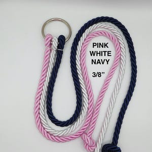Peut inclure: Un ensemble de trois cordes torsad&eacute;es rose, blanche et bleu marine, fix&eacute;es &agrave; un anneau m&eacute;tallique argent&eacute;. Les cordes ont un diam&egrave;tre de 0,95 cm et portent le texte imprim&eacute; PINK WHITE NAVY 3/8" sur la section de la corde blanche.