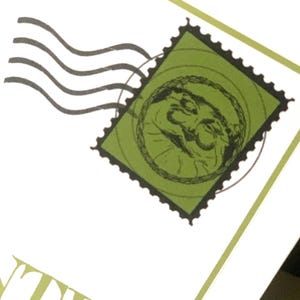 May include: A close-up of a green postage stamp with a black border and a circular design. The stamp features a detailed illustration within a circle. Black curved lines suggest movement, and the background is white.