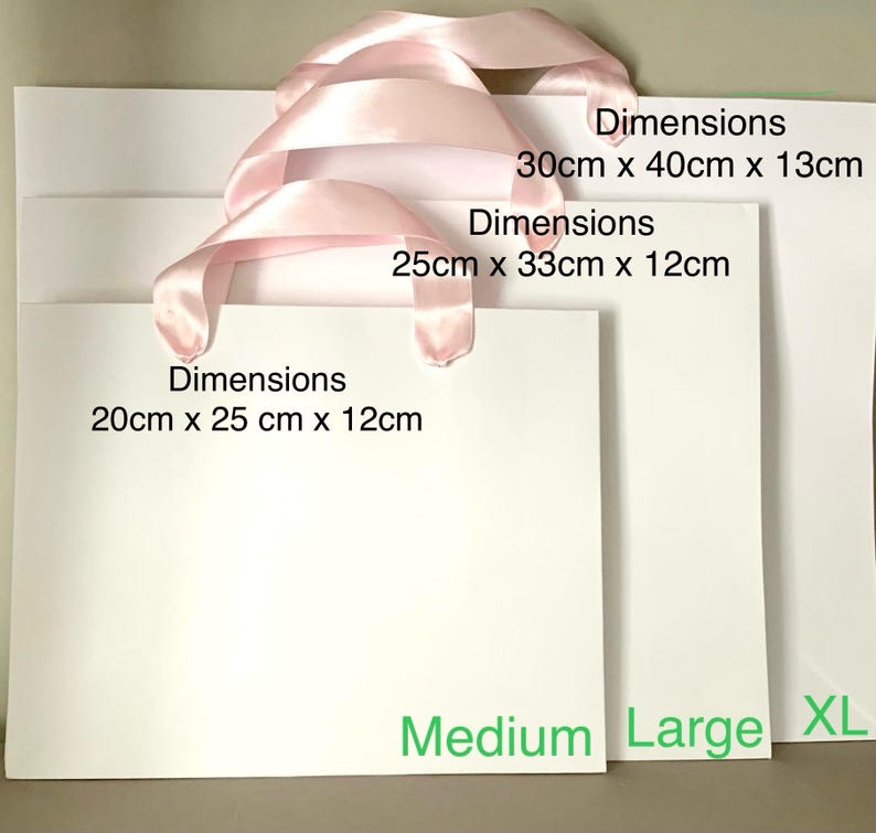 May include: Three white gift bags of varying sizes, each with a pink ribbon handle. The dimensions are listed on each bag: 20cm x 25cm x 12cm, 25cm x 33cm x 12cm, and 30cm x 40cm x 13cm. The bags are labeled Medium, Large, and XL.