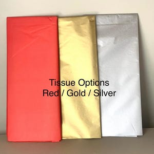 May include: Three rectangular sheets of tissue paper in red, gold, and silver. The text "Tissue Options Red / Gold / Silver" is printed on the image. The tissue paper is neatly folded and stacked, showcasing the color variations.