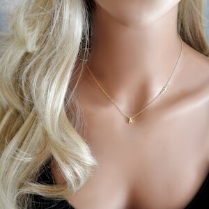 Puede incluir: Un collar de oro con un peque&ntilde;o colgante de letra y un delicado encanto de ala.