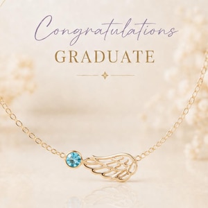 May include: Gold-colored angel wing necklace with a blue gemstone, displayed on a card with text that reads "Congratulations Graduate." The card also features text about the meaning of an angel wing.