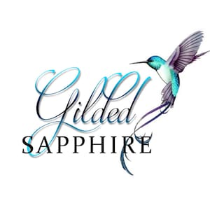 May include: A logo featuring the text Gilded in a blue cursive script and SAPPHIRE in a black serif font. To the right, a watercolour-style hummingbird with a bright blue head, white chest, and purple-toned wings is depicted in flight.