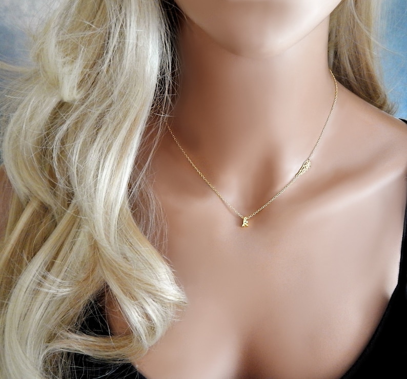 Puede incluir: Un collar de oro con un peque&ntilde;o colgante de letra y un delicado encanto de ala.