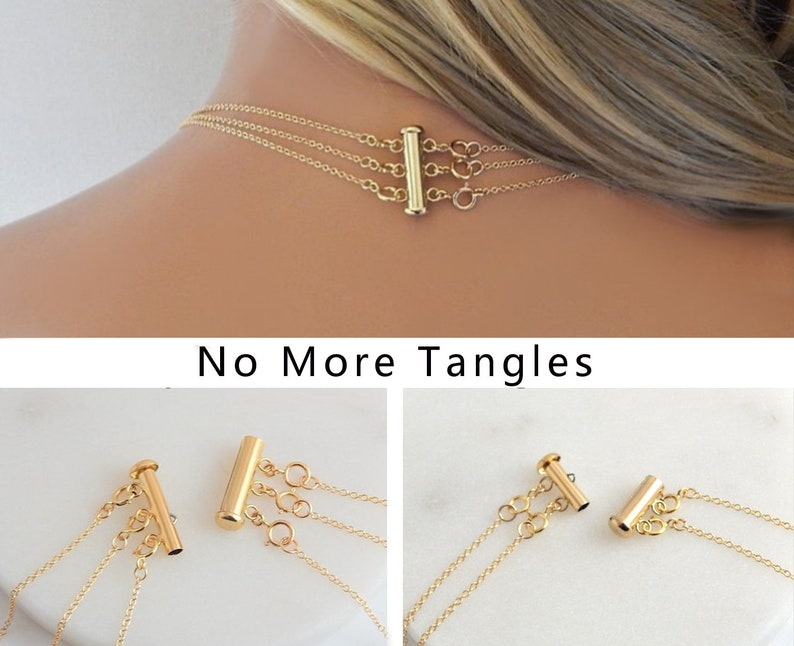 May include: Gold necklace clasp with three strands, designed to prevent tangling. The clasp is a gold-colored bar with three loops for attaching the necklace chains. The text "No More Tangles" is visible below the clasp.