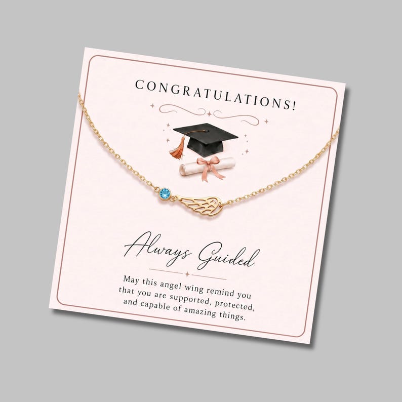 May include: A gold-colored necklace with a small blue gemstone and an angel wing pendant, displayed on a graduation-themed card. The card reads "CONGRATULATIONS!" and "Always Guided."