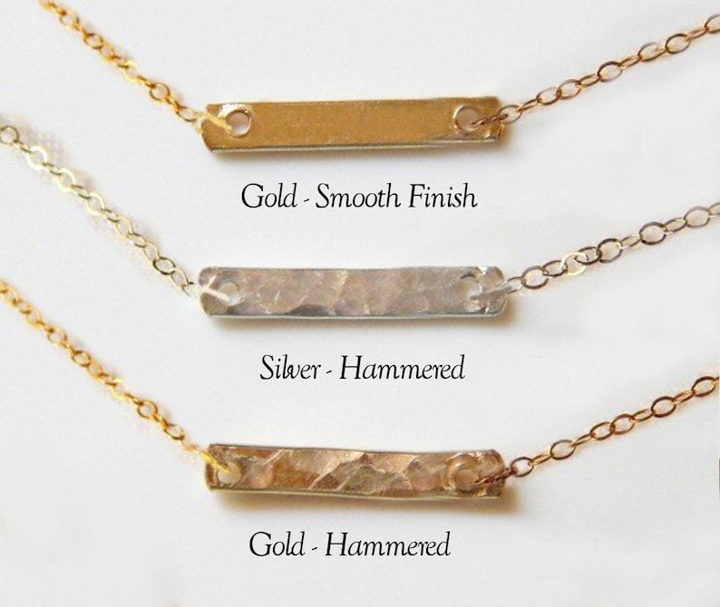 Puede incluir: Tres collares de barra horizontal con cadenas delicadas. El superior es una barra dorada con acabado liso. El medio es una barra plateada con textura martillada. El inferior es una barra dorada con textura martillada. Las etiquetas dicen Gold - Smooth Finish, Silver - Hammered y Gold - Hammered.