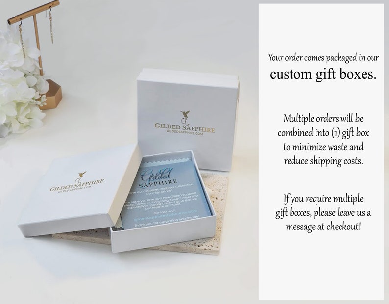 Może przedstawiać: Białe pudełka prezentowe z nadrukowanym logo "Gilded Sapphire" na g&oacute;rze. Pudełka są ułożone jedno na drugim. Tekst "Your order comes packaged in our custom gift boxes." jest wydrukowany po prawej stronie obrazu. Tekst "Multiple orders will be combined into (1) gift box to minimize waste and reduce shipping costs." jest wydrukowany pod pierwszym tekstem. Tekst "If you require multiple gift boxes, please leave us a message at checkout!" jest wydrukowany pod drugim tekstem.