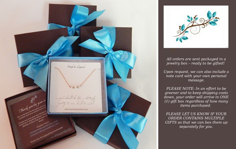 May include: Several brown gift boxes tied with light blue satin ribbons. One box is open, revealing a delicate gold necklace with small, round charms on a white card. The card has text that reads "Simple & Layered".