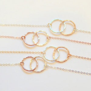May include: Four delicate gold necklaces with a double circle pendant design. Each necklace features a thin chain and a hammered metal pendant.