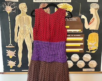 May include: A sleeveless dress with a red, purple, and brown polka dot pattern. The dress has a fitted bodice and a flowing skirt.