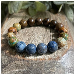 May include: A bracelet made of brown, green, and blue gemstone beads. The beads are round and have a natural, polished finish.