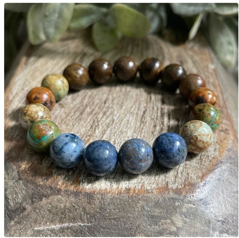May include: A bracelet made of brown, green, and blue gemstone beads. The beads are round and have a natural, polished finish.