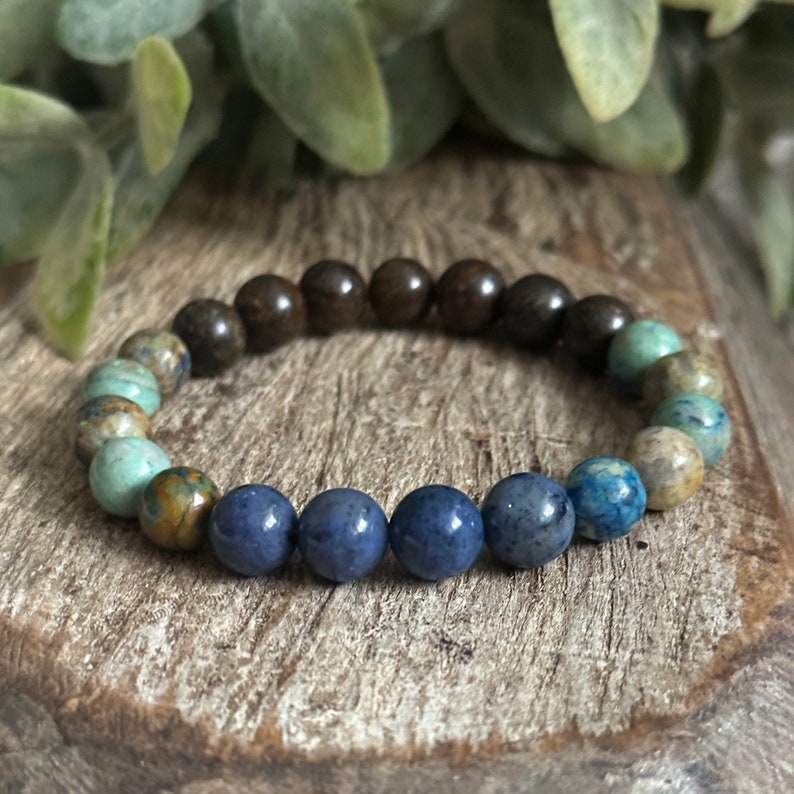 May include: A beaded bracelet with brown, blue, and green stones. The bracelet is made of natural stones and has a simple design.