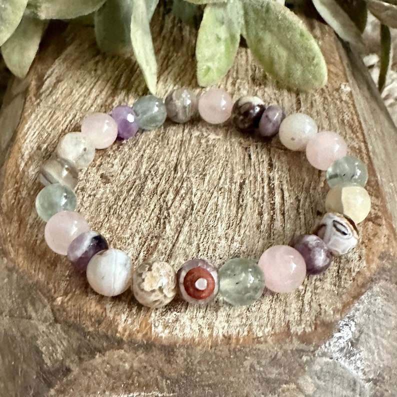 Op de afbeelding: Een veelkleurige kralen armband met roze, groene, witte en paarse kralen. De armband is gemaakt van natuurlijke stenen en is een prachtig en uniek sieraad.
