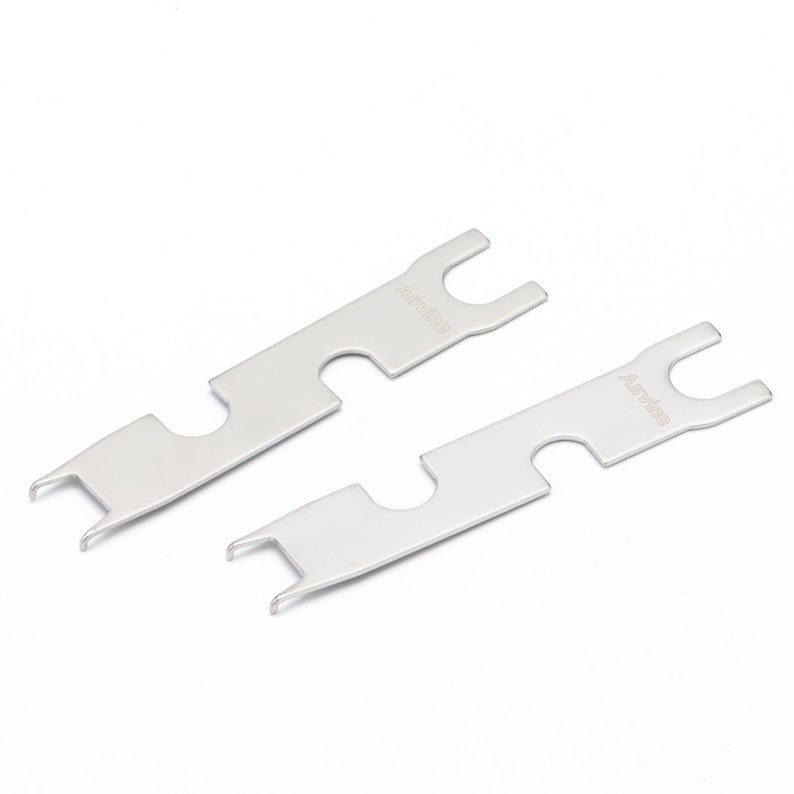 May include: Two silver metal tools with a U-shaped end and a hook on the other end. The tools are labeled "Assydia" on the top and "Assydia" on the bottom.