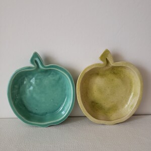 May include: Two ceramic apple-shaped dishes, one green and one yellow, with a glossy finish.