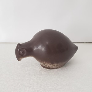 May include: A brown ceramic bird figurine with a rounded body and a small, pointed beak. The bird has a textured surface and is set against a white background. This decorative item is suitable for home decor.