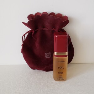 May include: A small bottle of Alix Gres perfume in a red velvet drawstring bag. The bottle is clear glass with a red cap and a gold label. The label reads "Alix Gres,  'Eau de Gres', Vaporisateur Natural Spray, Eau de Toilette, 1 fl. oz. - 30 ml."