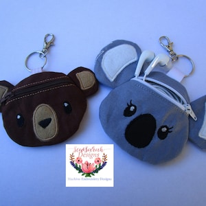 May include: Two small zippered pouches with animal faces. The brown pouch has a bear face and the blue pouch has a koala face. Both pouches have a zipper closure and are attached to key rings.
