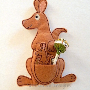 Può includere: Un canguro di feltro marrone con una tasca che contiene un canguro di feltro marrone più piccolo. Un lecca-lecca verde e bianco sporge dalla tasca.