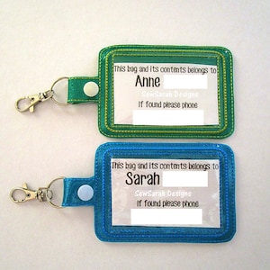 May include: Two turquoise and green fabric keychains with clear plastic windows. The windows have text that reads "This bag and its contents belongs to" followed by a blank space for a name. The text "SewSarah Designs" and "If found please phone" are printed below the blank space. The keychains have a silver metal clasp.
