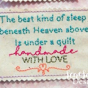 Può includere: Un'etichetta in tessuto bianco con ricami rosa, blu e verdi. L'etichetta recita "Il miglior tipo di sonno sotto il cielo, è sotto un trapunta fatta a mano con amore".