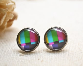 May include: A pair of silver stud earrings featuring a colourful static television screen design. The earrings are round and have a black border.