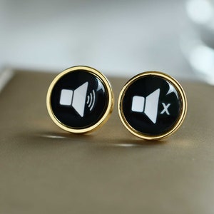 May include: A pair of gold cufflinks with black and white sound icons. One cufflink has a speaker icon with sound waves, the other has a speaker icon with a cross through it.