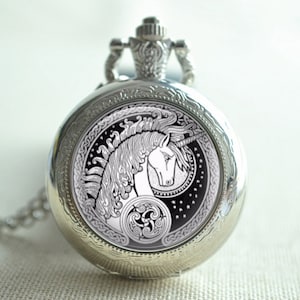 May include: Silver pocket watch with a black and white image of a unicorn with a Celtic knot design. The watch has a chain attached.
