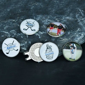 May include: Set of six personalized golf ball markers with different designs.  The markers feature names, golf clubs, golf balls, and photos.  The markers are white with blue and black accents.