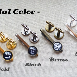 May include: Four sets of cufflinks and tie clips in gold, black, brass, and silver. Each set features a different design, including a black and white "Why not" design, a black and white "Mother of the Bride" design, a black and white monogram "SAK" design, and a black and white monogram "CHS" design.