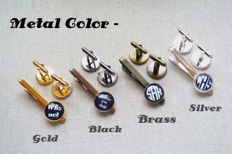 May include: Four sets of cufflinks and tie clips in gold, black, brass, and silver. Each set features a different design, including a black and white "Why not" design, a black and white "Mother of the Bride" design, a black and white monogram "SAK" design, and a black and white monogram "CHS" design.