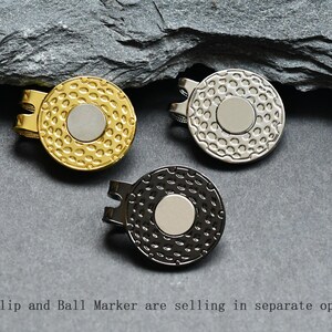 May include: Three golf ball markers, one gold, one silver, and one black, with a textured surface and a smooth, round center.  Hat Clip and Ball Marker are selling in separate options!