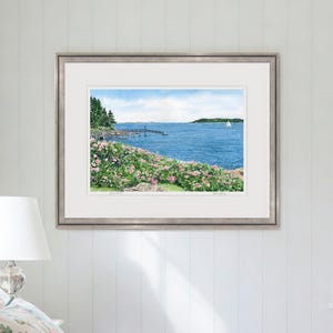 Large framed watercolor art print of Spruce Point showcased in a sunlit room, emphasizing Boothbay Harbor’s rocky coast and blooming roses.