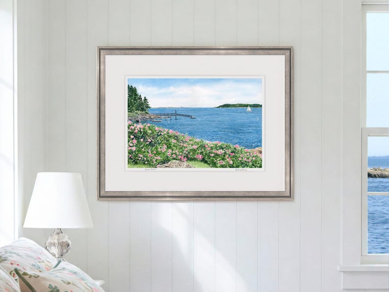 Large framed watercolor art print of Spruce Point showcased in a sunlit room, emphasizing Boothbay Harbor’s rocky coast and blooming roses.