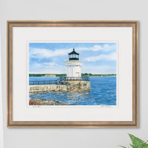 Framed watercolor art print of Bug Light staged in a bright interior, showing Portland Breakwater Light with calm blue harbor waters.